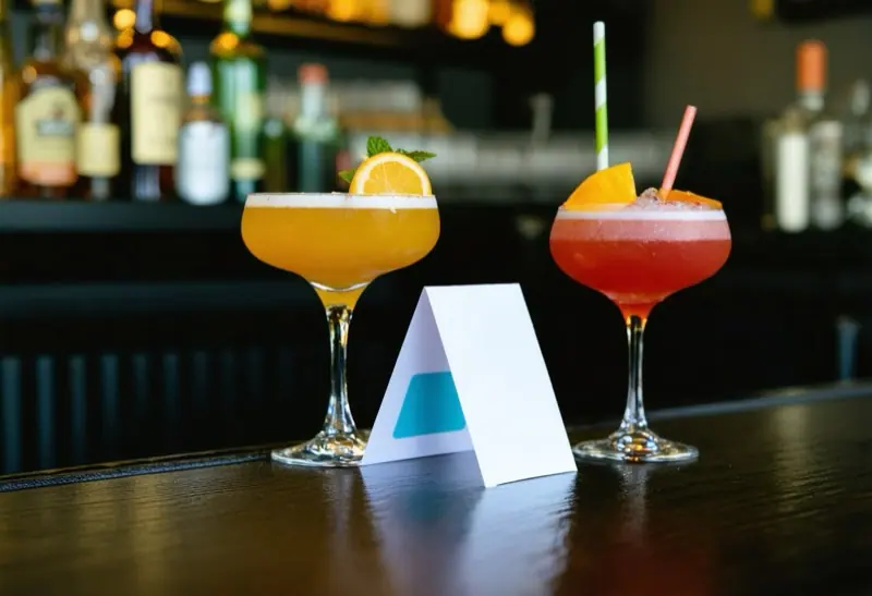 White tent card standing on a bar top between two cocktails
